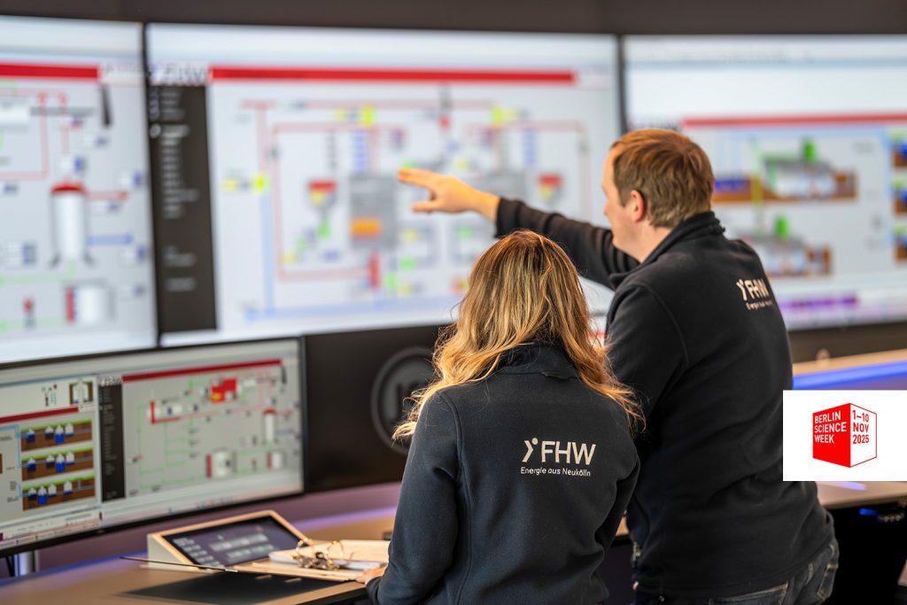 Zwei Personen in Jacken mit FHW-Logo arbeiten an Computern und großen Monitoren mit technischen Diagrammen in der neuen Systemwarte von FHW